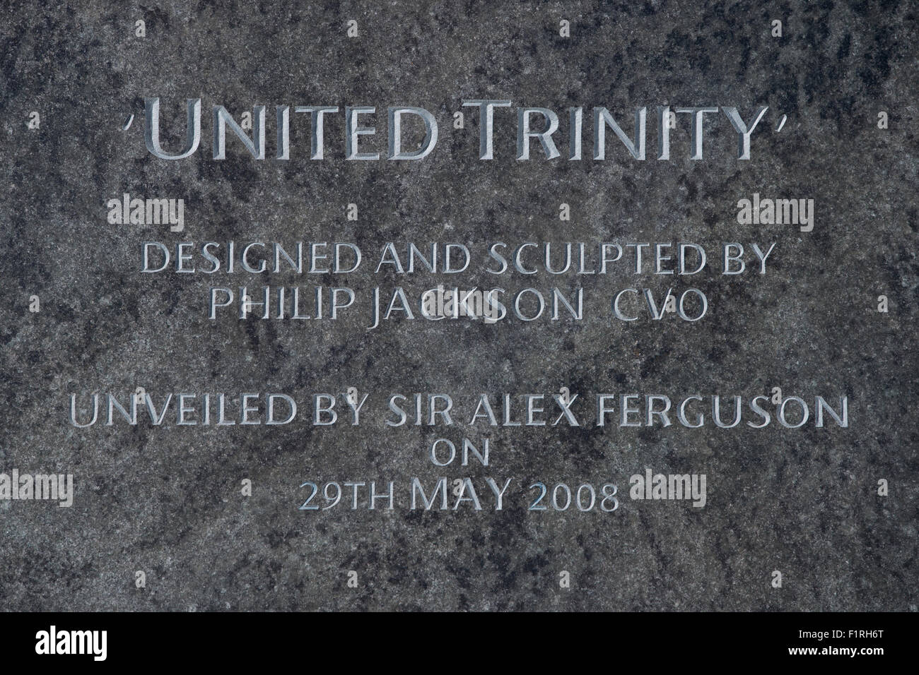 Die Plakette unter der Trinity United-Statue in der Nähe von Old Trafford Stadion, Heimat des Manchester United Football Club. Stockfoto