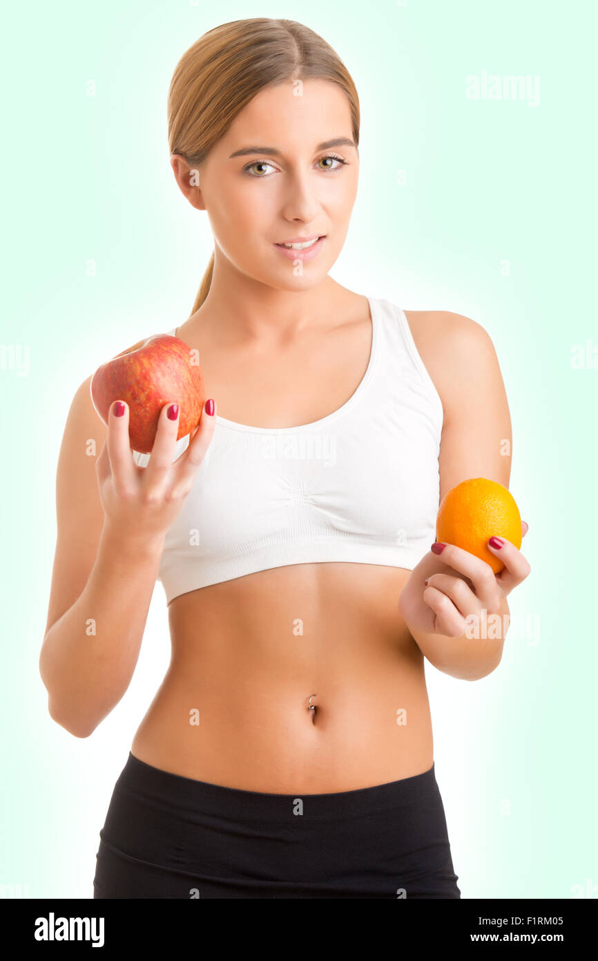 Fit Frau hält eine Orange und ein Apfel auf einem hellen Hintergrund Stockfoto