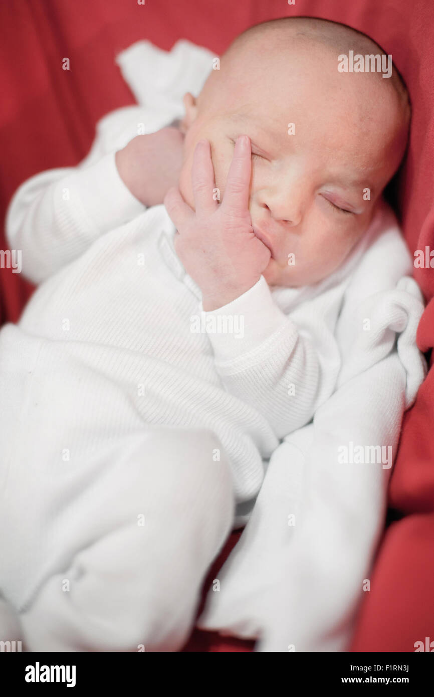 Niedlichen neugeborenen Mädchen schläft mit Finger im Mund Stockfoto