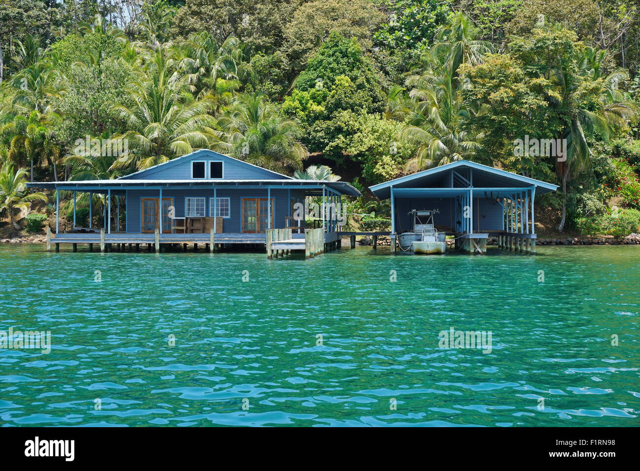 Haus und Boot Tropenhaus oberhalb des Meeres mit üppiger Vegetation an der Küste, Panama, Mittelamerika Stockfoto