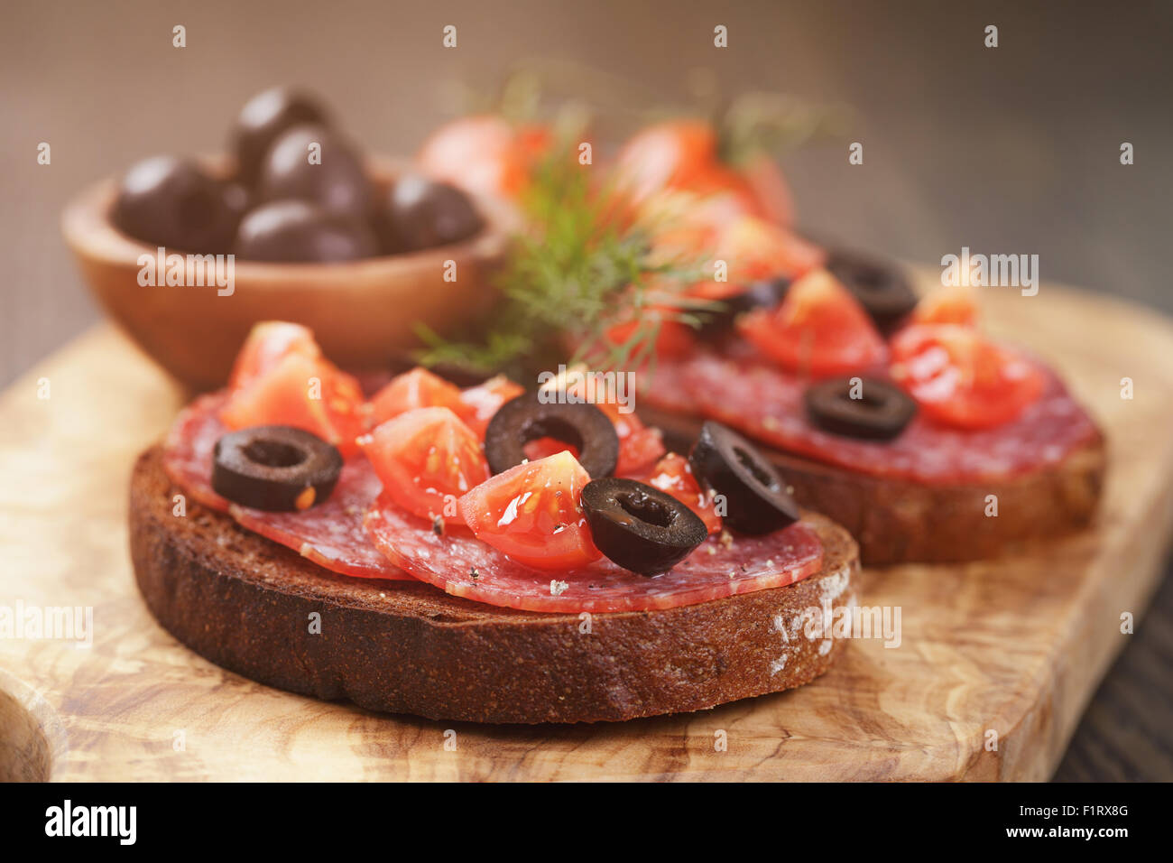 Roggen-Sandwich mit Salami und Tomaten auf Holztisch Stockfoto