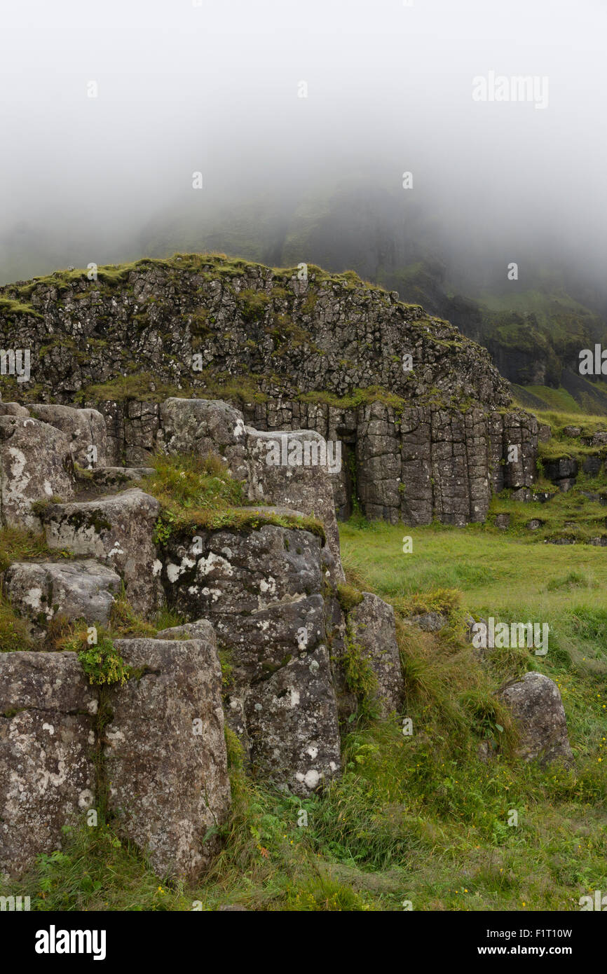 Die atemberaubende natürliche Felsformation von Basaltsäulen bei Dverghamrar (die Zwergklippen) mit Klippen dahinter, die in den Nebel steigen, Island Stockfoto