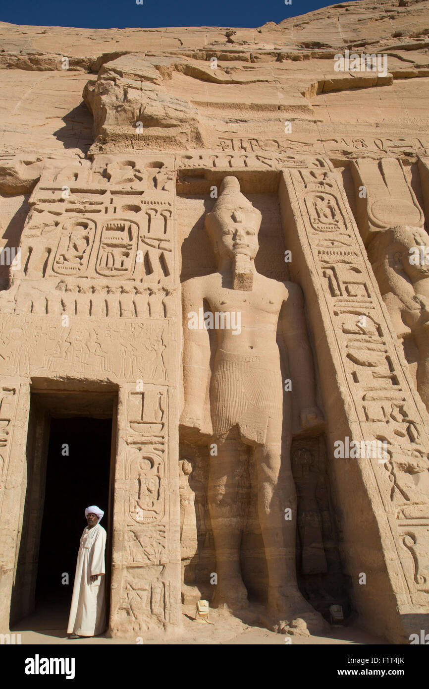 Lokale Mann am Eingang des Tempels, Ramses II Statue rechts, Hathor Tempel der Königin Nefertari, UNESCO, Abu Simbel, Ägypten Stockfoto