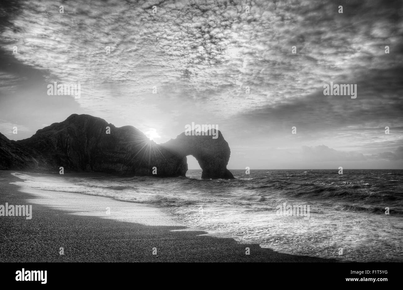 Winter-Sonnenaufgang hinter Durdle Door auf Jurassic Coast in schwarz / weiß Stockfoto