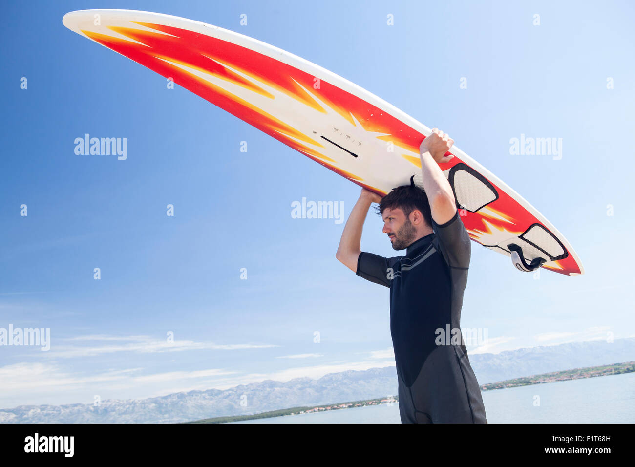 Surfer Holding Surfbrett über Kopf Stockfoto