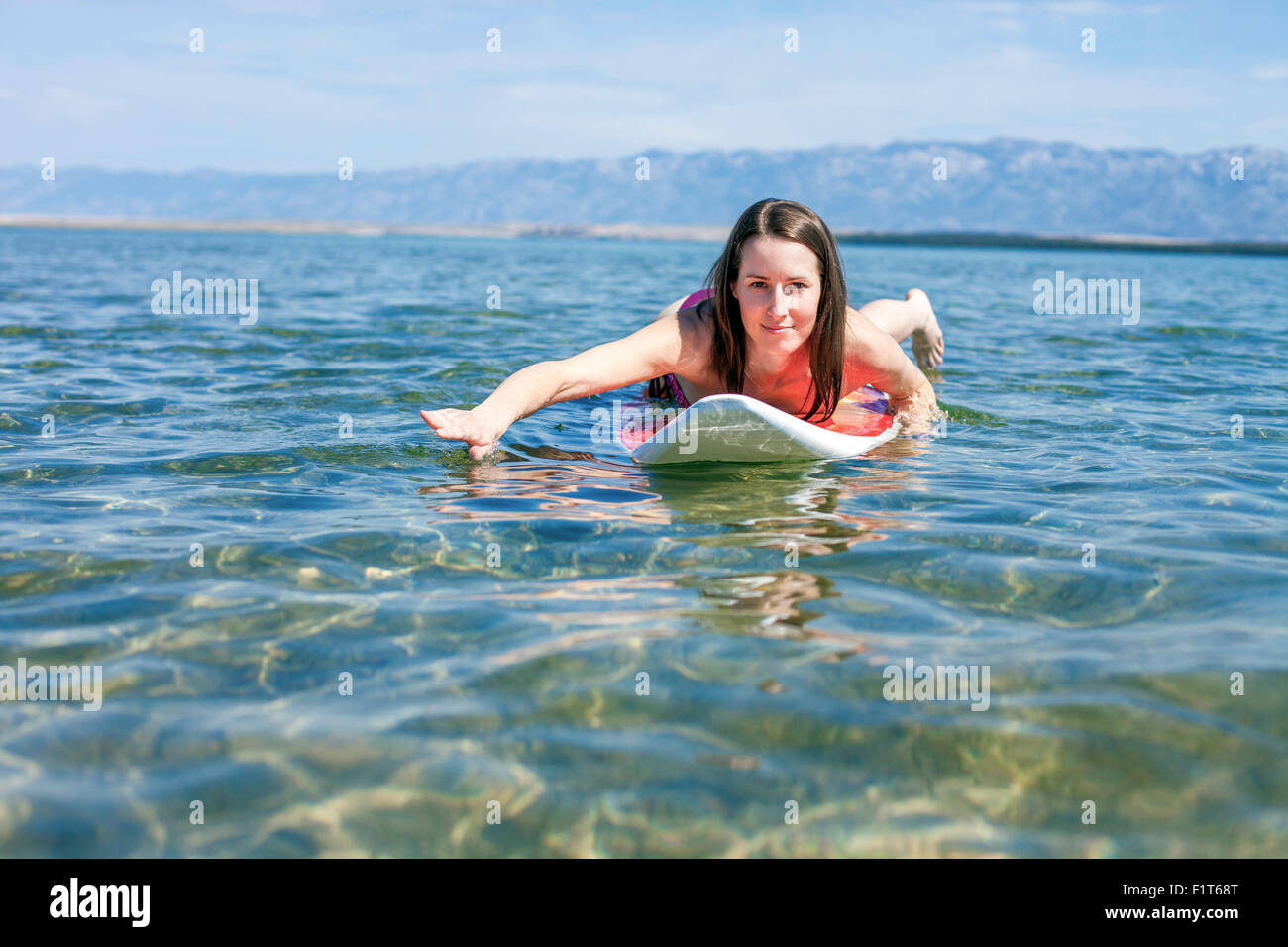 Frau liegend auf Surfbrett Stockfoto