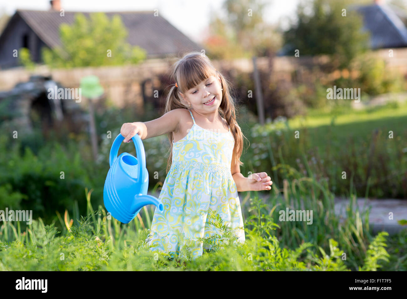 Niedliche kleine Mädchen Bewässerung von Pflanzen im Garten Stockfoto