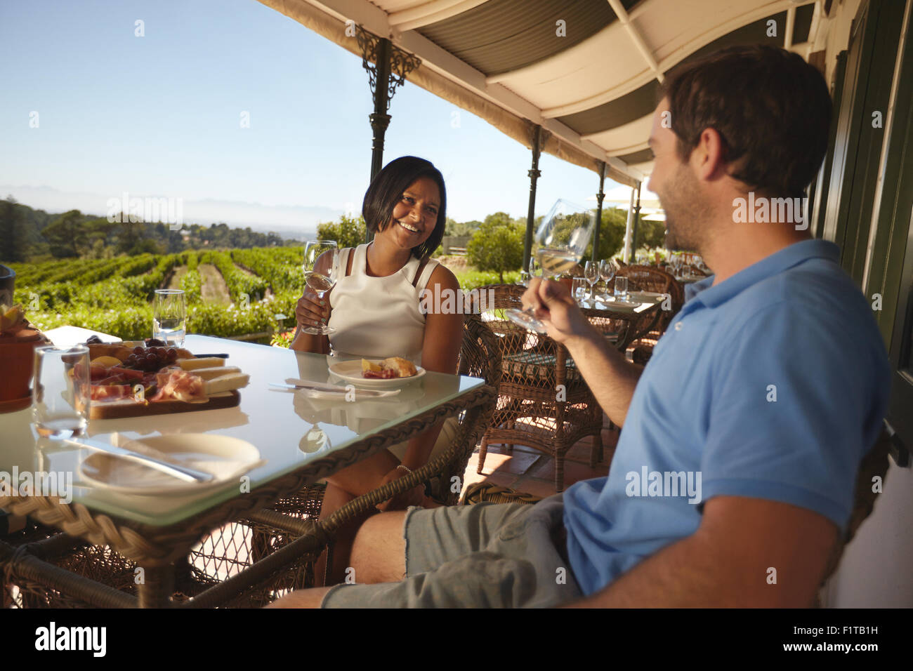 Junges Paar im Urlaub trinken Wein in einem Restaurant. Mann und Frau in einem Wein bar Restaurant von einem Weinberg. Stockfoto