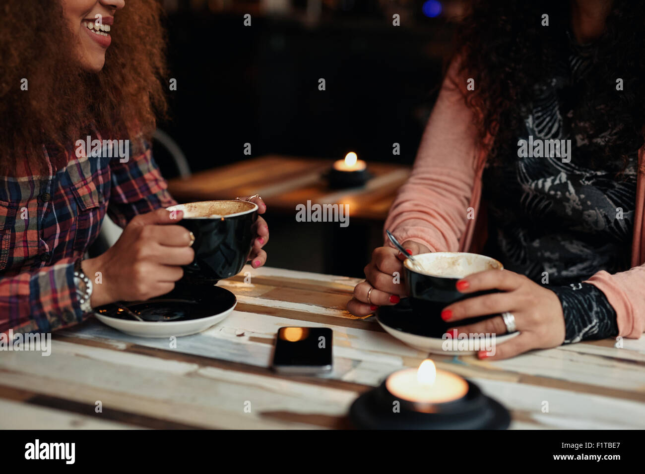 Aufnahme von zwei Frauen sitzen im Restaurant hält Kaffee beschnitten. Freundinnen Kaffee trinken an einem Tisch Stockfoto