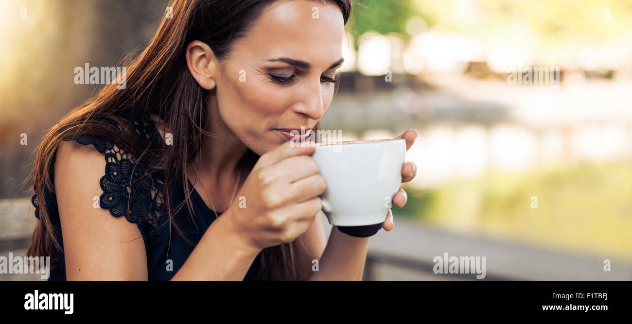 Porträt der jungen Frau mit einem aromatischen Kaffee in Händen hautnah. Weibliche Kaffeetrinken im Café. Stockfoto