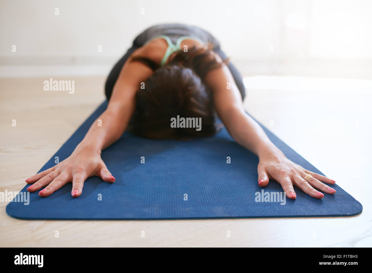Frau Dehnübung auf Yoga-Matte zu tun. Fitness Frauen Yoga auf Gymnastikmatte in Turnhalle durchführen. Kind-Pose, Balasana. Stockfoto