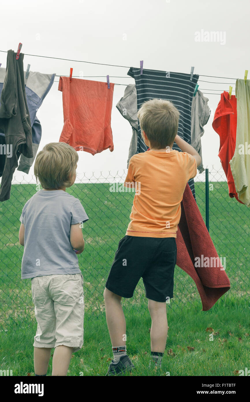 Zwei junge Burschen, die Wäsche auf einer Wäscheleine aufhängen. Stockfoto