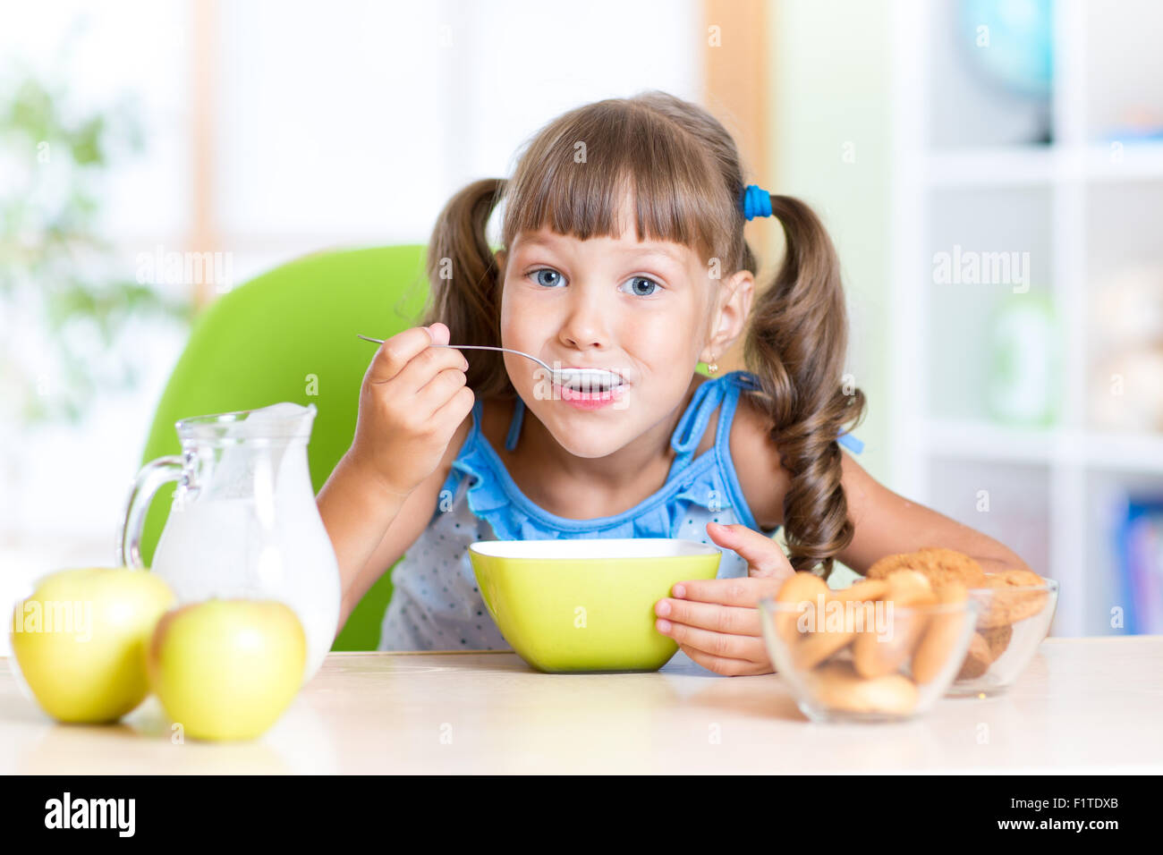 niedliche kleine Mädchen essen Müsli mit Milch im Kindergarten Stockfoto