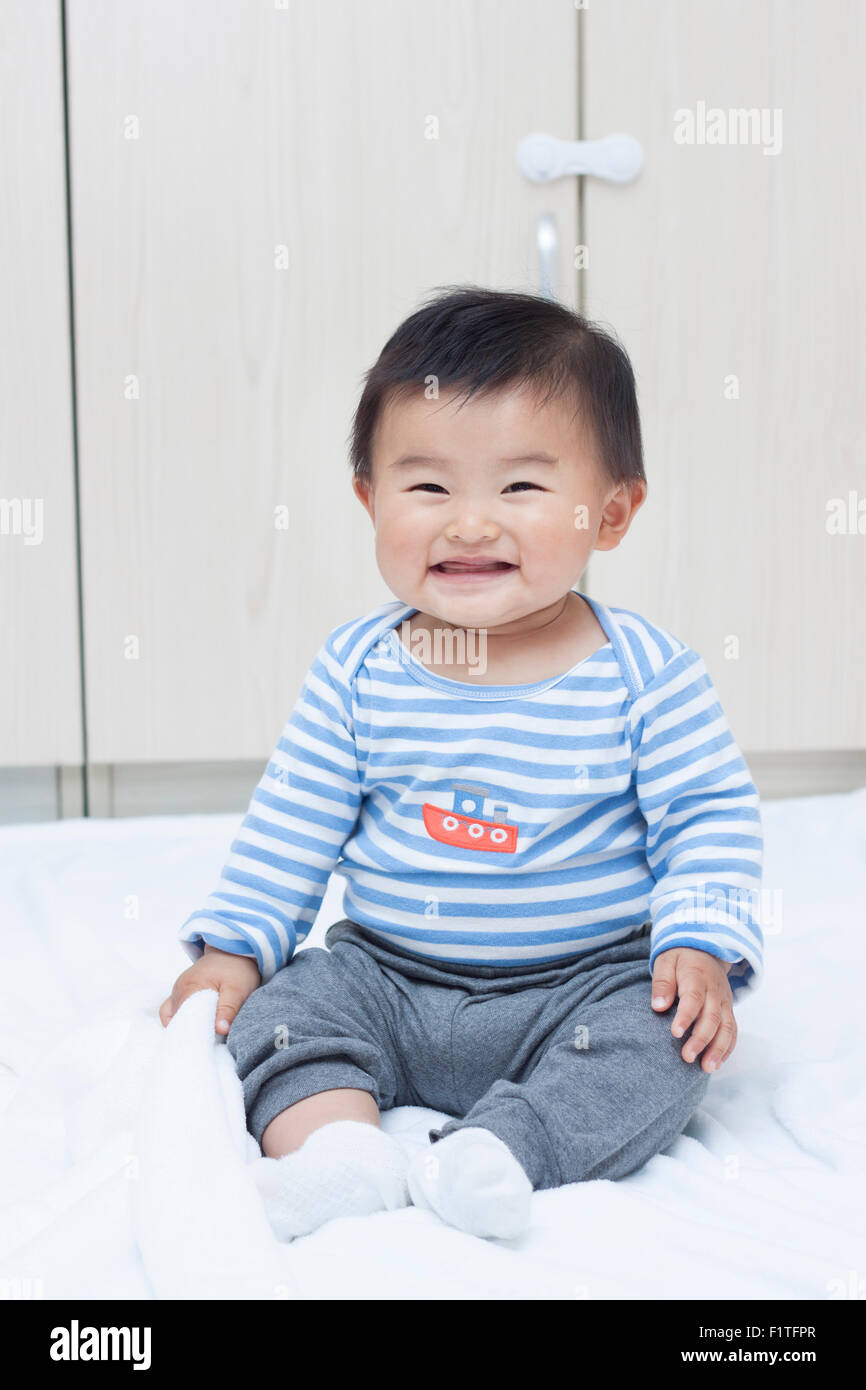 Niedlichen chinesischen Baby Junge sitzt auf einer weißen Decke Stockfoto