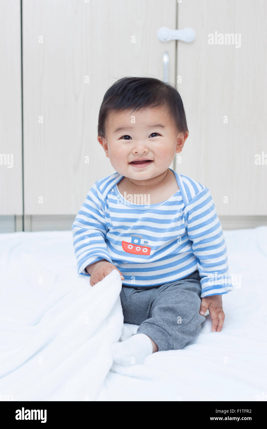 Niedlichen chinesischen Baby Junge sitzt auf einer weißen Decke Stockfoto