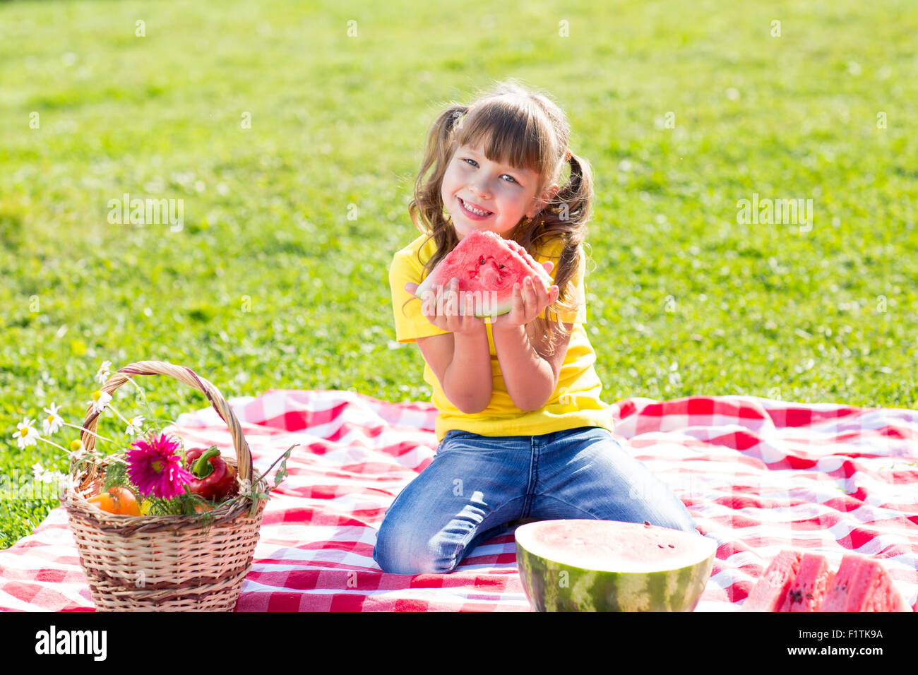 niedliche kleine Mädchen essen Wassermelone auf dem Rasen im Sommer Stockfoto