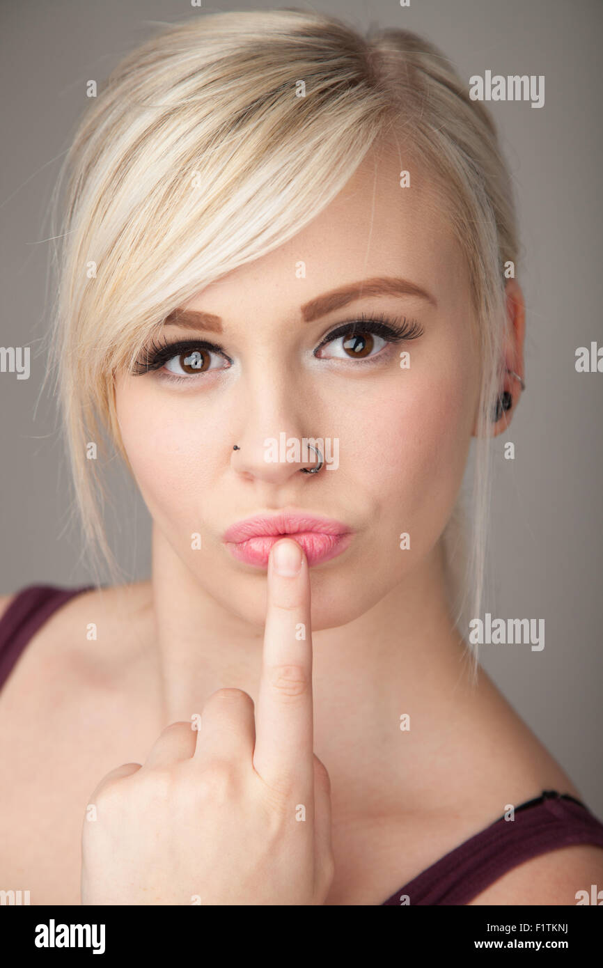 Ziemlich junges Mädchen mit einem Finger drückte gegen ihre Lippen. Stockfoto