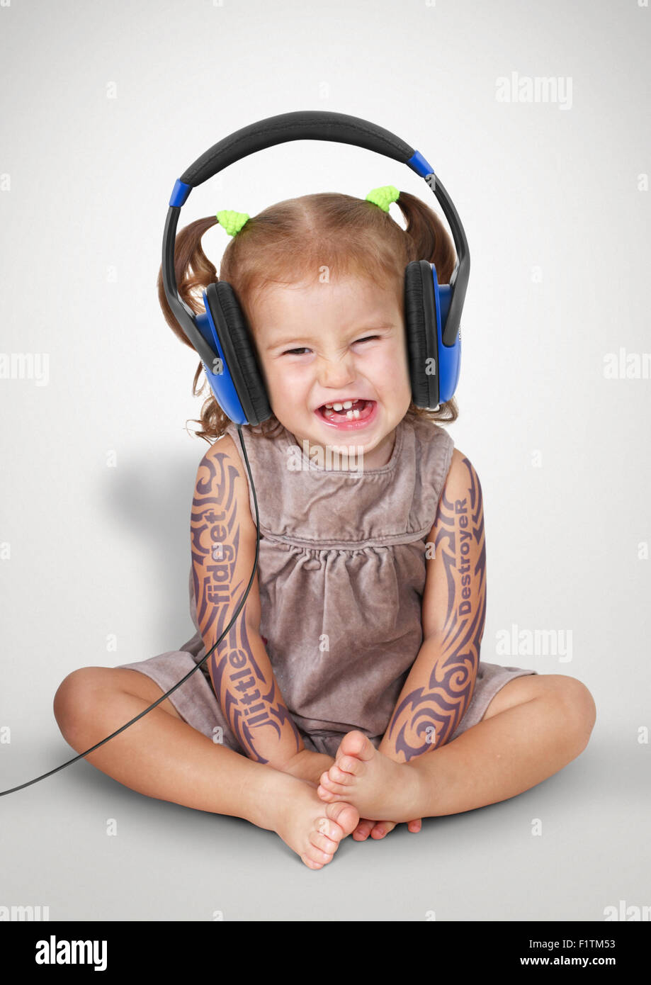 Lustiges Kind Mädchen mit Tatoo Musik im Kopfhörer hören Stockfoto