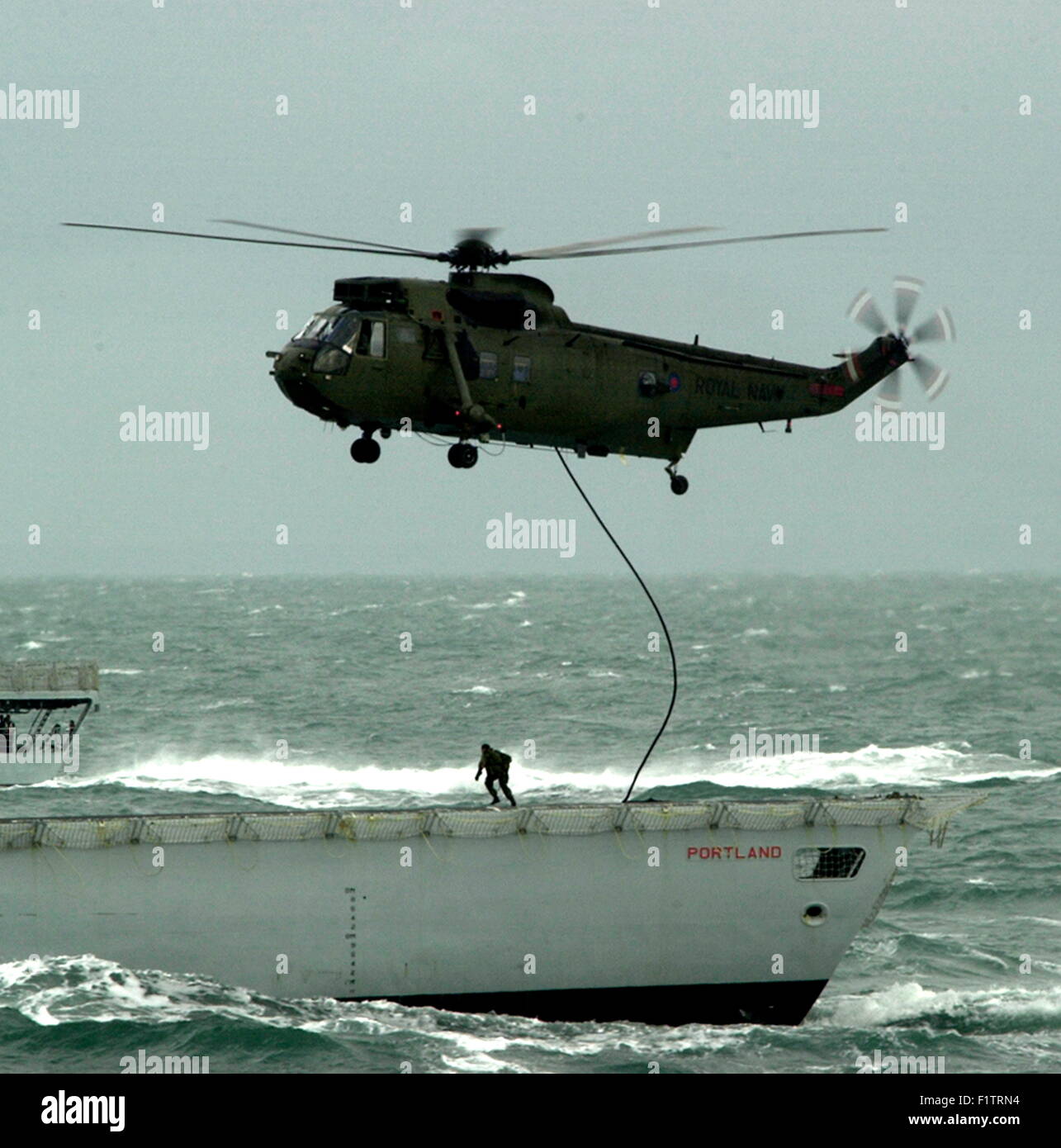 AJAXNETPHOTO - 5. OKTOBER 2004 AUF SEE, KANAL. -MEER PERSONAL COLLEGE-TAGEN. SEA KING EIN SEIL NACH UNTEN ÜBUNG MIT ROYAL MARINES AUF DEM FLUGDECK DER HMS PORTLAND DURCHFÜHREN.  FOTO: JONATHAN EASTLAND/AJAX.  REF: 40510 935. Stockfoto