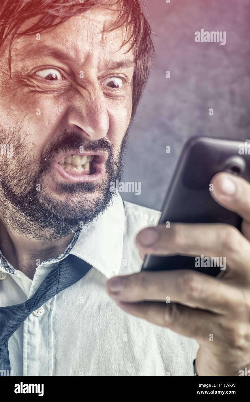 Porträt von wütenden Geschäftsmann erhielt frustrierend SMS-Nachricht oder E-mail auf mobile smart Phone, selektiven Fokus auf Gesicht Stockfoto