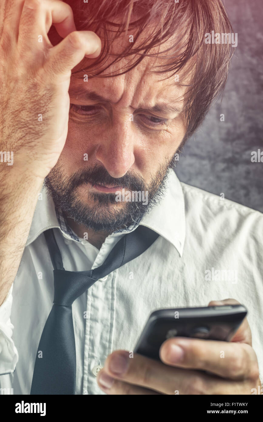 Porträt von besorgt Geschäftsmann erhielt schlechte Nachrichten per SMS-Nachricht oder E-mail auf mobile smart Phone, selektiven Fokus auf Gesicht Stockfoto