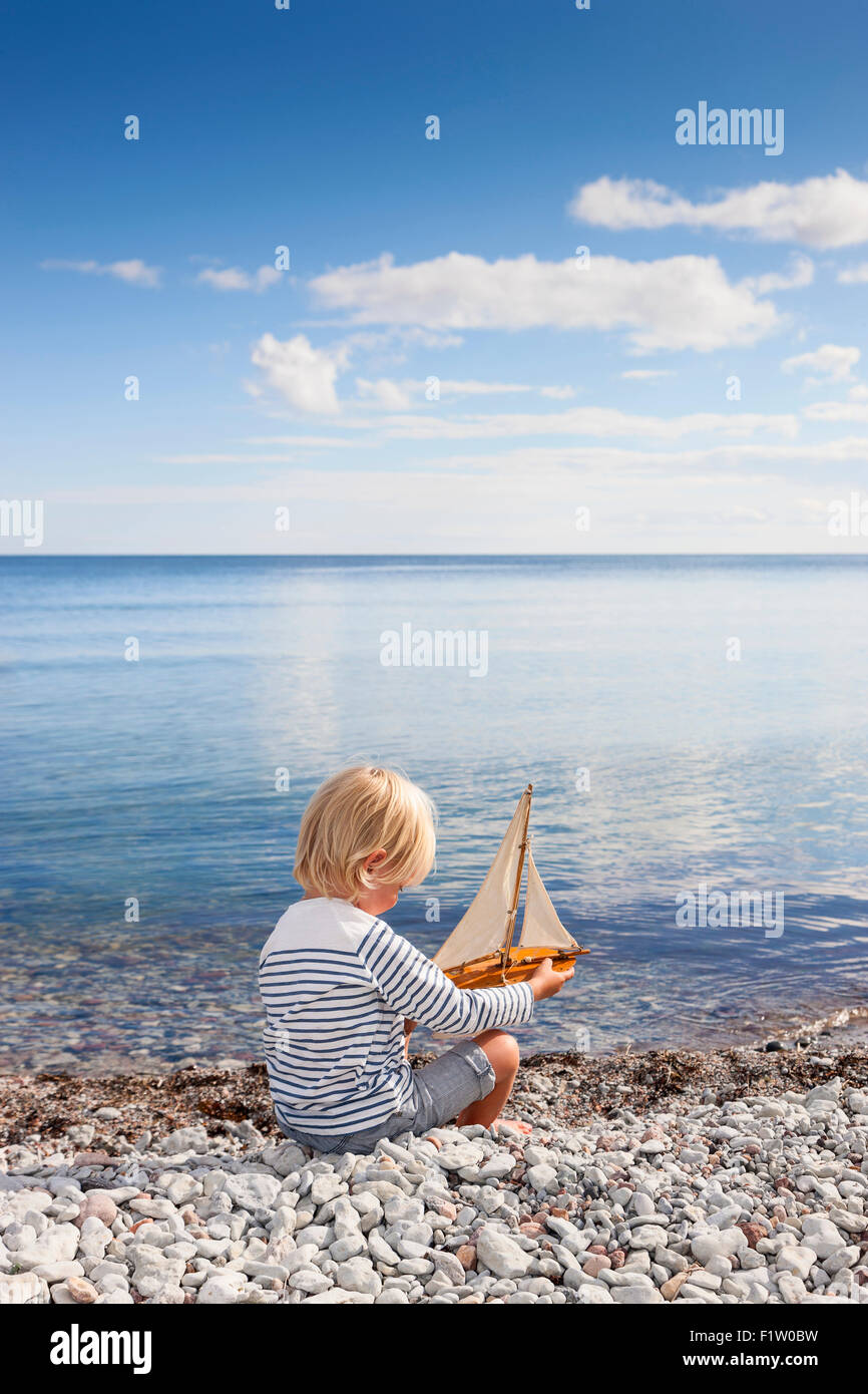 blonde junge am Strand mit einem Modell-Segelboot, Gotland, Schweden, model release Stockfoto