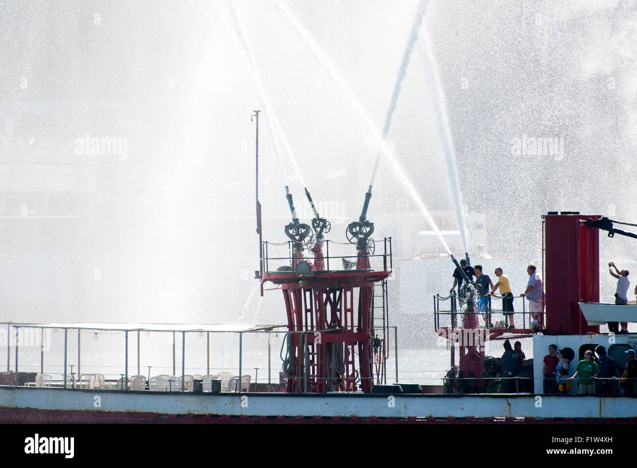 Die historischen Feuerwehrlöschboot John J. Harvey Spritzen festliche Federn von Wasser auf dem Hudson River in New York Harbor. Stockfoto