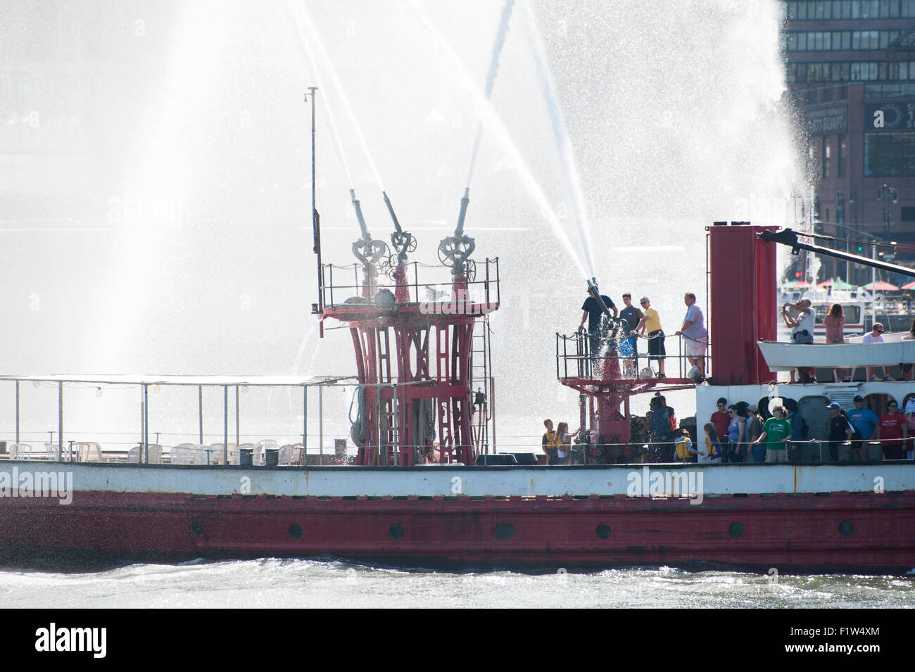 Die historischen Feuerwehrlöschboot John J. Harvey Spritzen festliche Federn von Wasser auf dem Hudson River in New York Harbor. Stockfoto