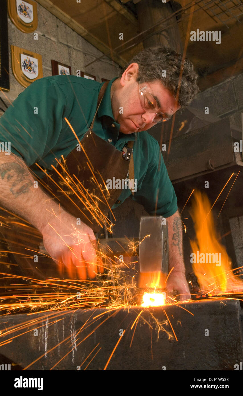 Schmied Simon Grant-Jones Hämmern heiße Metall mit Funken fliegen, in seiner Schmiede, wo er ein Handwerker-metalworker.a UK ist Stockfoto