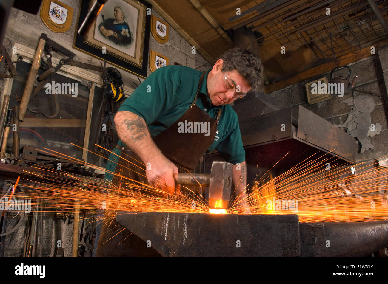 Schmied Simon Grant-Jones Hämmern heiße Metall mit Funken fliegen, in seiner Schmiede, wo er ein Handwerker-metalworker.a UK ist Stockfoto