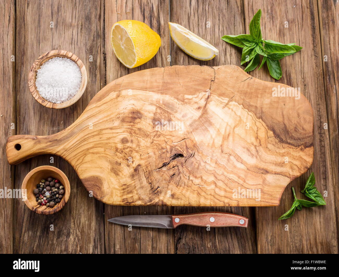 Olive-Schneidebrett und Gewürze auf einem Holztisch. Stockfoto