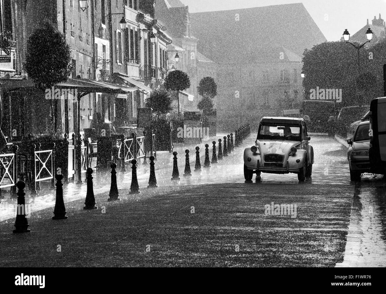 Französische Straße Szene klassische Citroen 2CV Auto fahren entlang einer Straße bei starkem Regen, Ambroise Indre et Loire Frankreich Europa Stockfoto