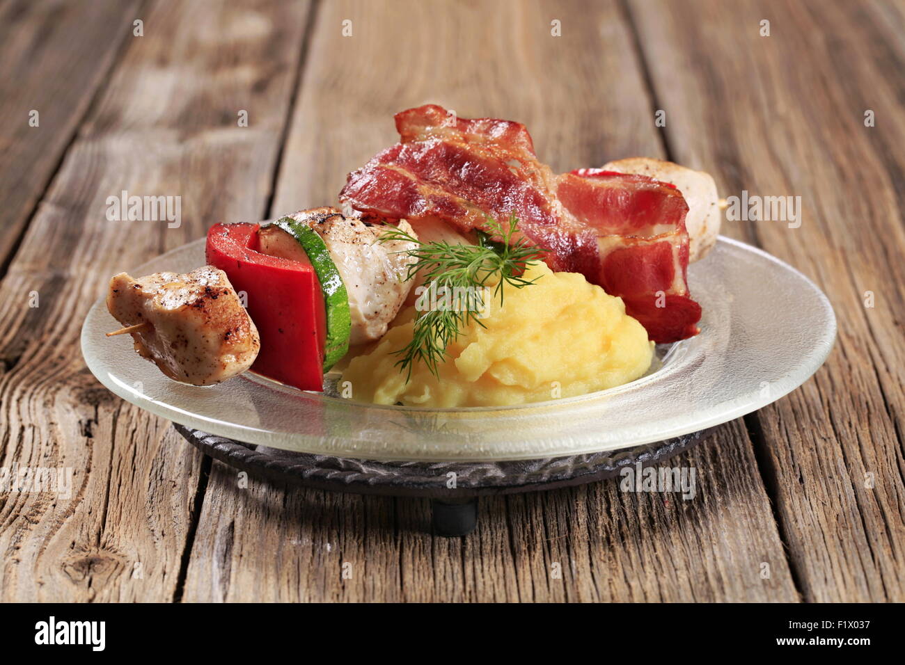 Huhn Schaschlik mit Stampfkartoffeln und Scheibe Speck Stockfoto