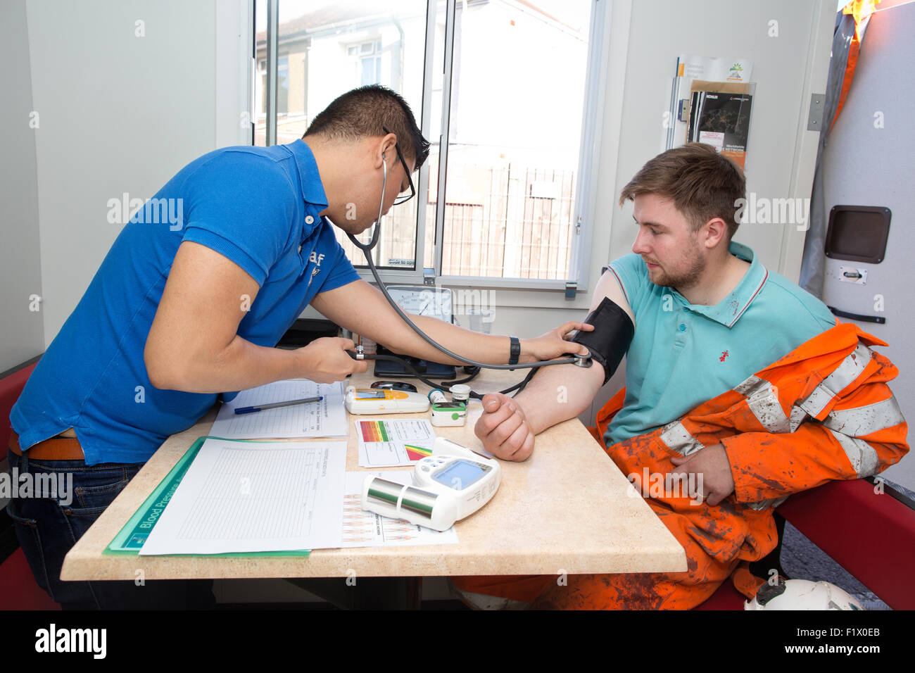 Bauarbeiter unter Blutdruck Test und der allgemeine Gesundheitszustand überprüfen vor Ort, England, UK Stockfoto