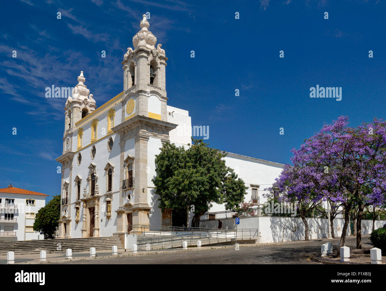 Faro, die Igreja Carmo Barockkirche mit Jacaranda-Bäume in Blüte, Algarve, Portugal Stockfoto