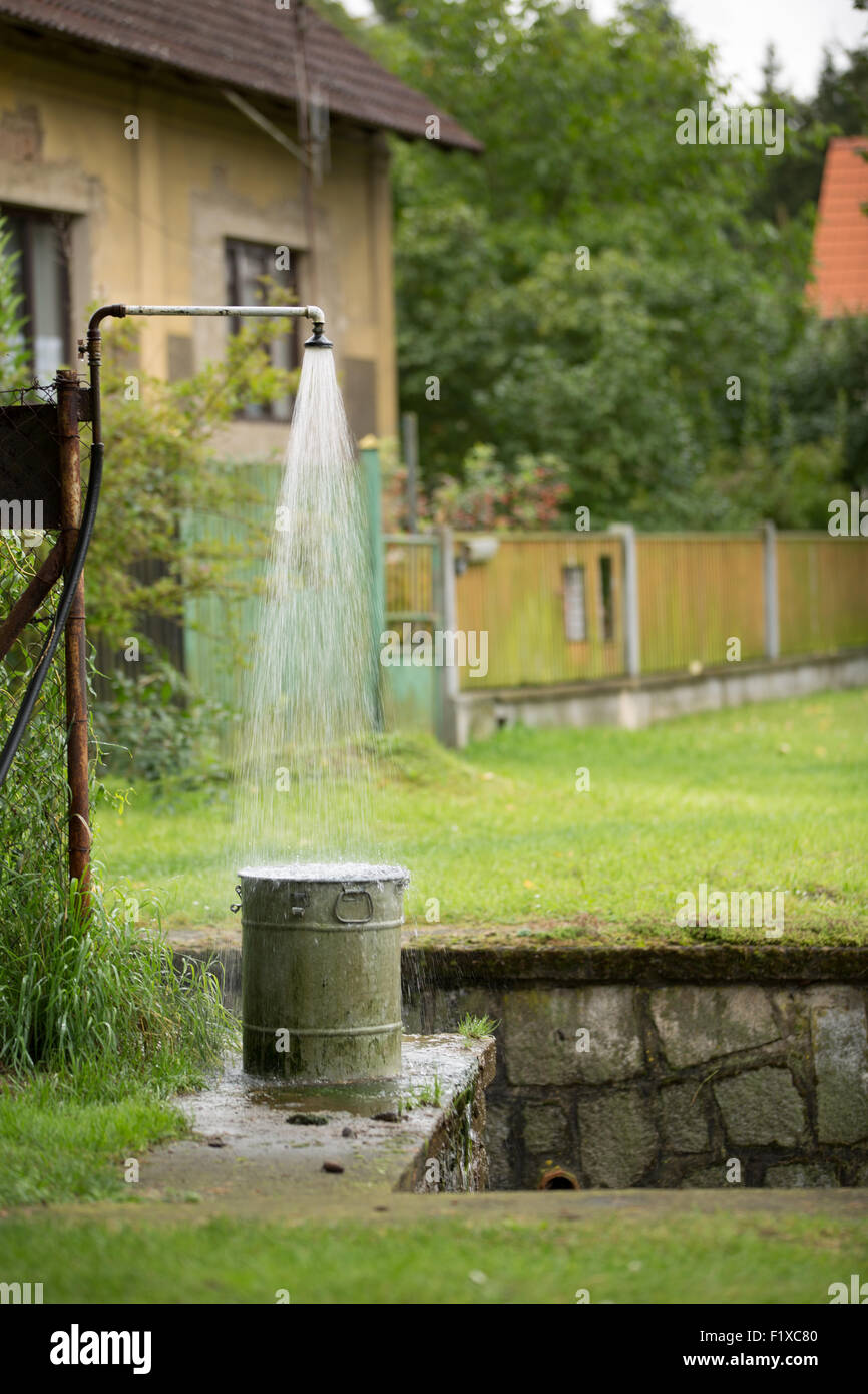 Eine unbefristete Dusche Wasser Spritzen in einem überlaufenden Eimer am Rand des Abflusses Stockfoto