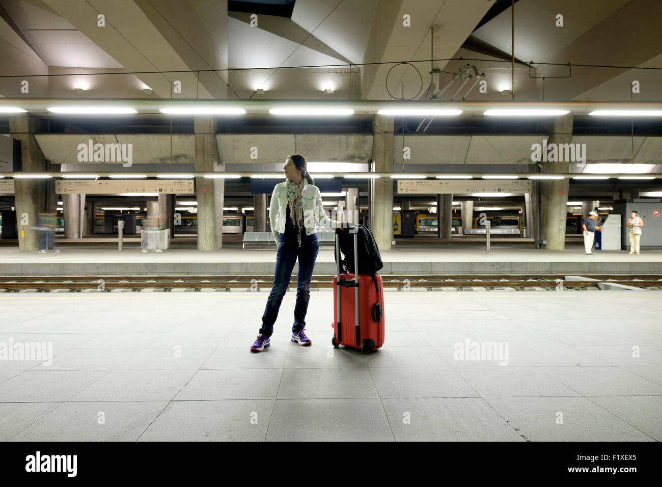 Passagier mit roten Rollen Trolley Koffer warten auf einen Zug auf einer Bahn-Bahnsteig Stockfoto