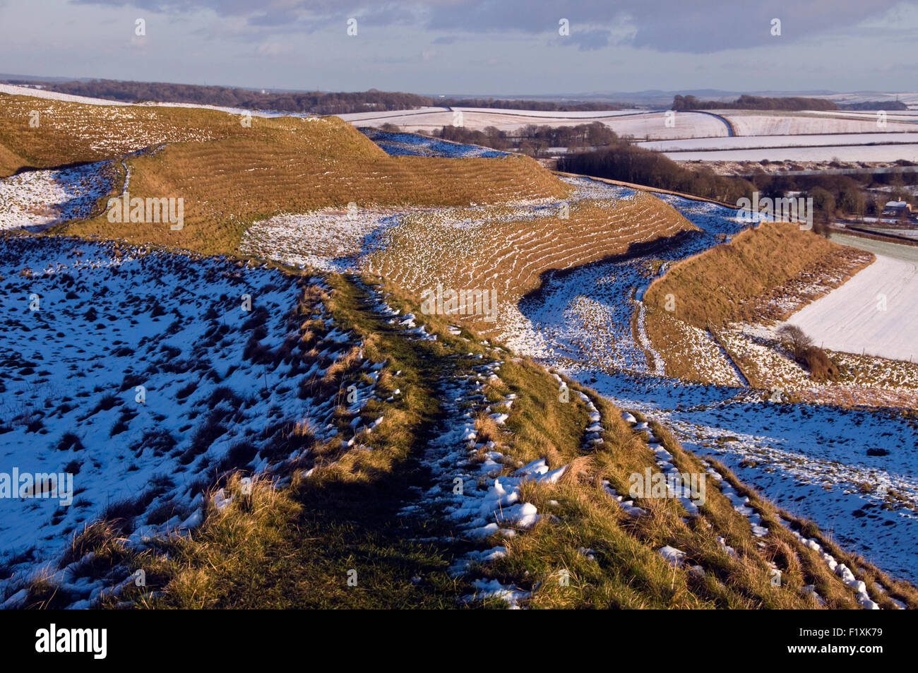 Schnee bedeckt teilweise die Eisenzeit Erde Funktionsweise von Maiden Castle in der Nähe von Dorchester in Dorset, England, UK Stockfoto