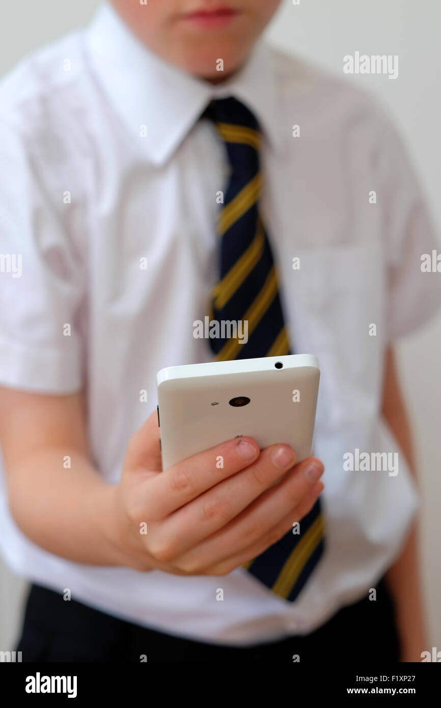 Ein Schulkind in Uniform mit seinem Mobiltelefon (SMS) UK Stockfoto