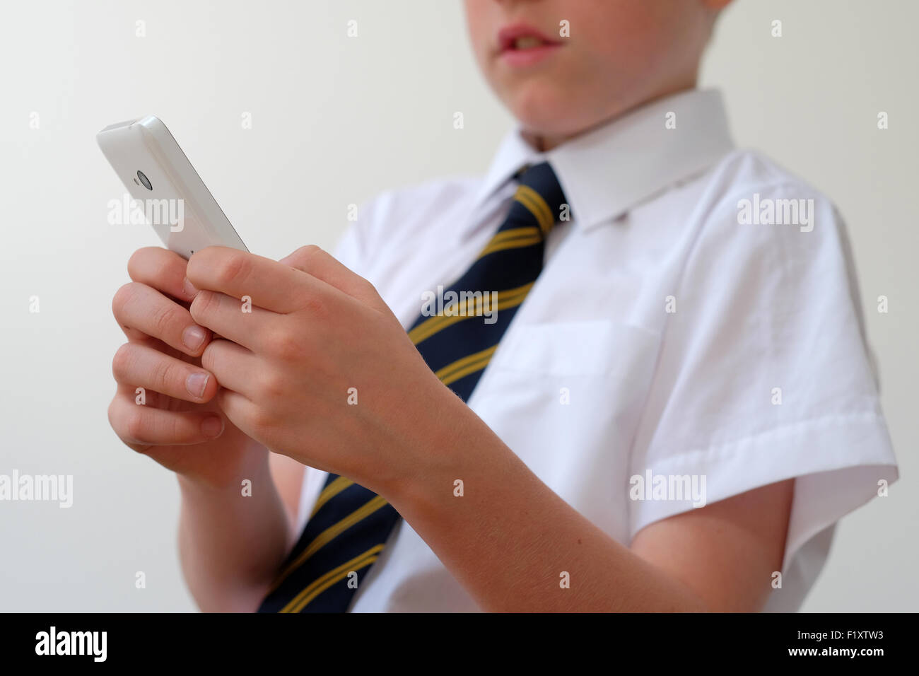 Ein Schulkind in Uniform mit seinem Mobiltelefon (SMS) UK Stockfoto