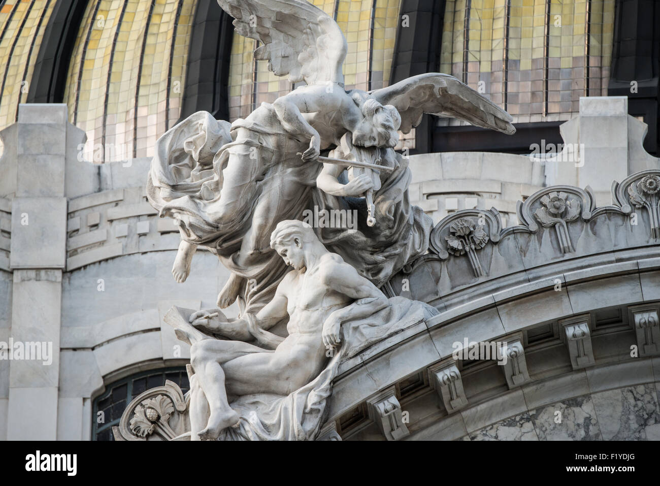 MEXIKO-STADT, Mexiko – kunstvoll verzierte Skulpturenfiguren, die Musik und Kunst darstellen, zieren den Giebel über dem Haupteingang des Palacio de Bellas Artes und demonstrieren die raffinierten Elemente des neoklassizistischen und Jugendstildesigns. Diese dekorativen Skulpturen veranschaulichen die detaillierte architektonische Ornamentik, die Mexikos führendes Kulturzentrum auszeichnet. Das skulpturale Programm trägt zur Pracht der Hauptfassade des Palastes bei. Stockfoto