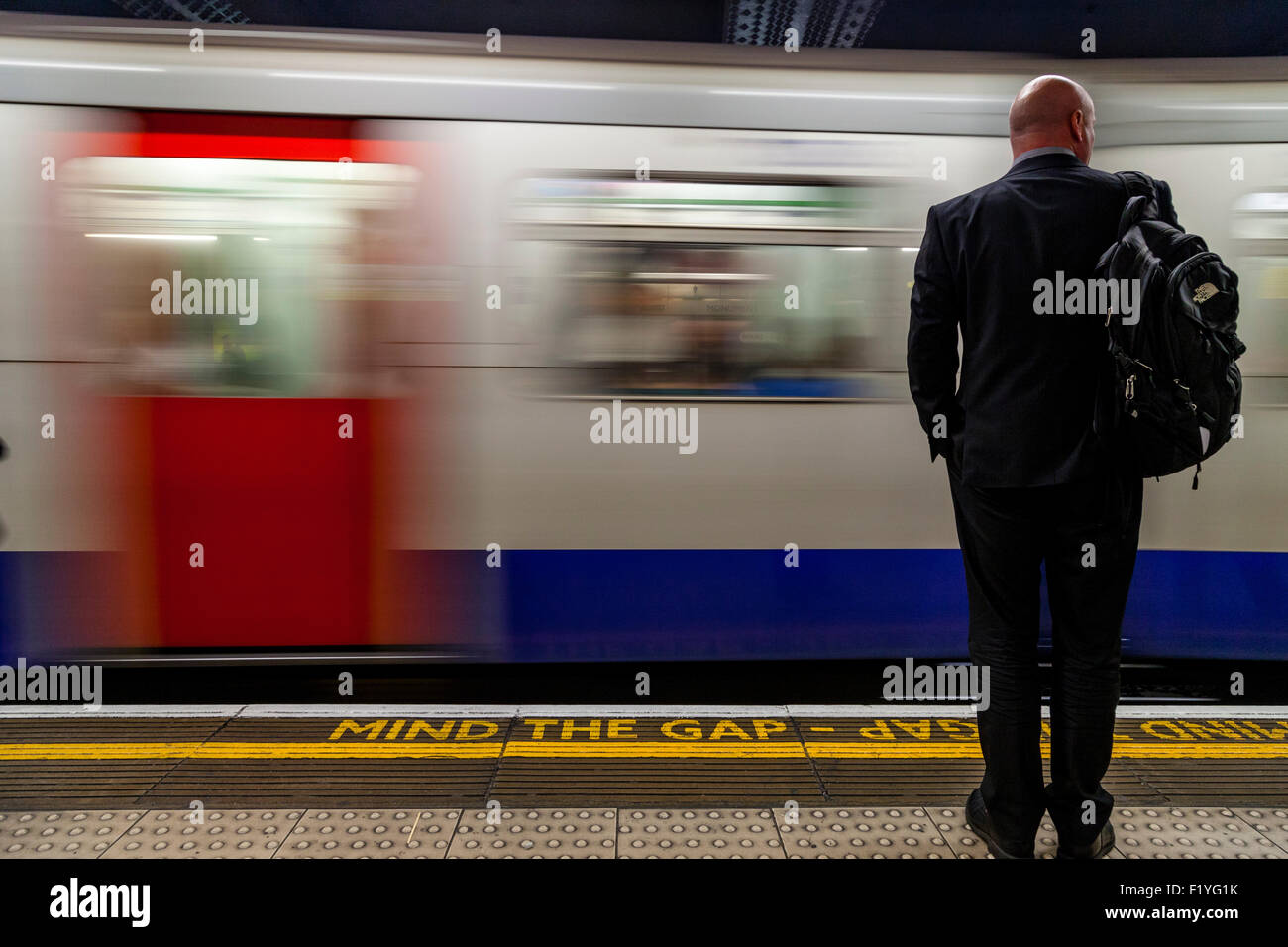 Ein Geschäftsmann im Anzug wartet auf einen Zug, der Londoner U-Bahn, London, England Stockfoto