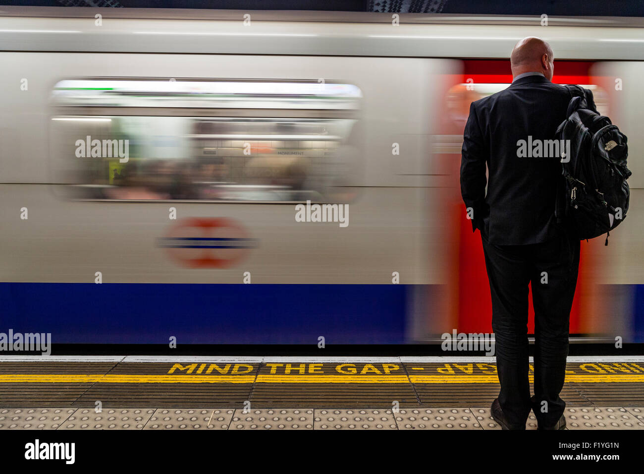 Ein Geschäftsmann im Anzug wartet auf einen Zug, der Londoner U-Bahn, London, England Stockfoto