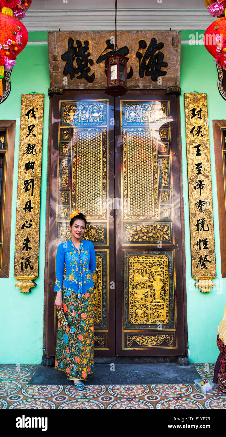 Eine chinesische Frau stehend durch eine traditionelle chinesische Haus in der UNESCO-Welterbe in Georgetown, Penang. Stockfoto