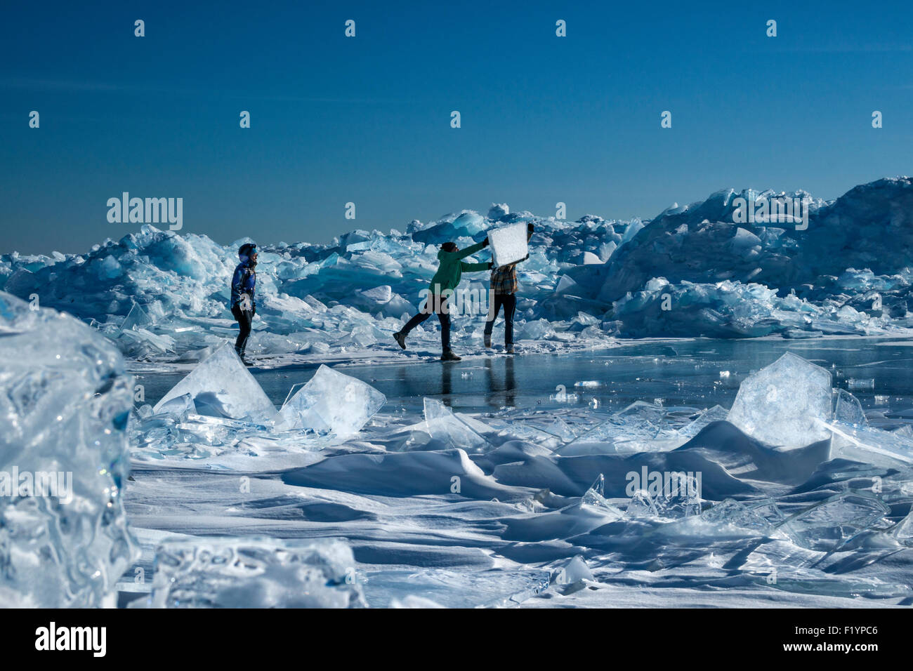 Zwei Erwachsene Männer spielen mit Eisbrocken Teller stapelten sich aus einem Druck-Grat entlang Lake Superior, North Shore im Winter, Stockfoto