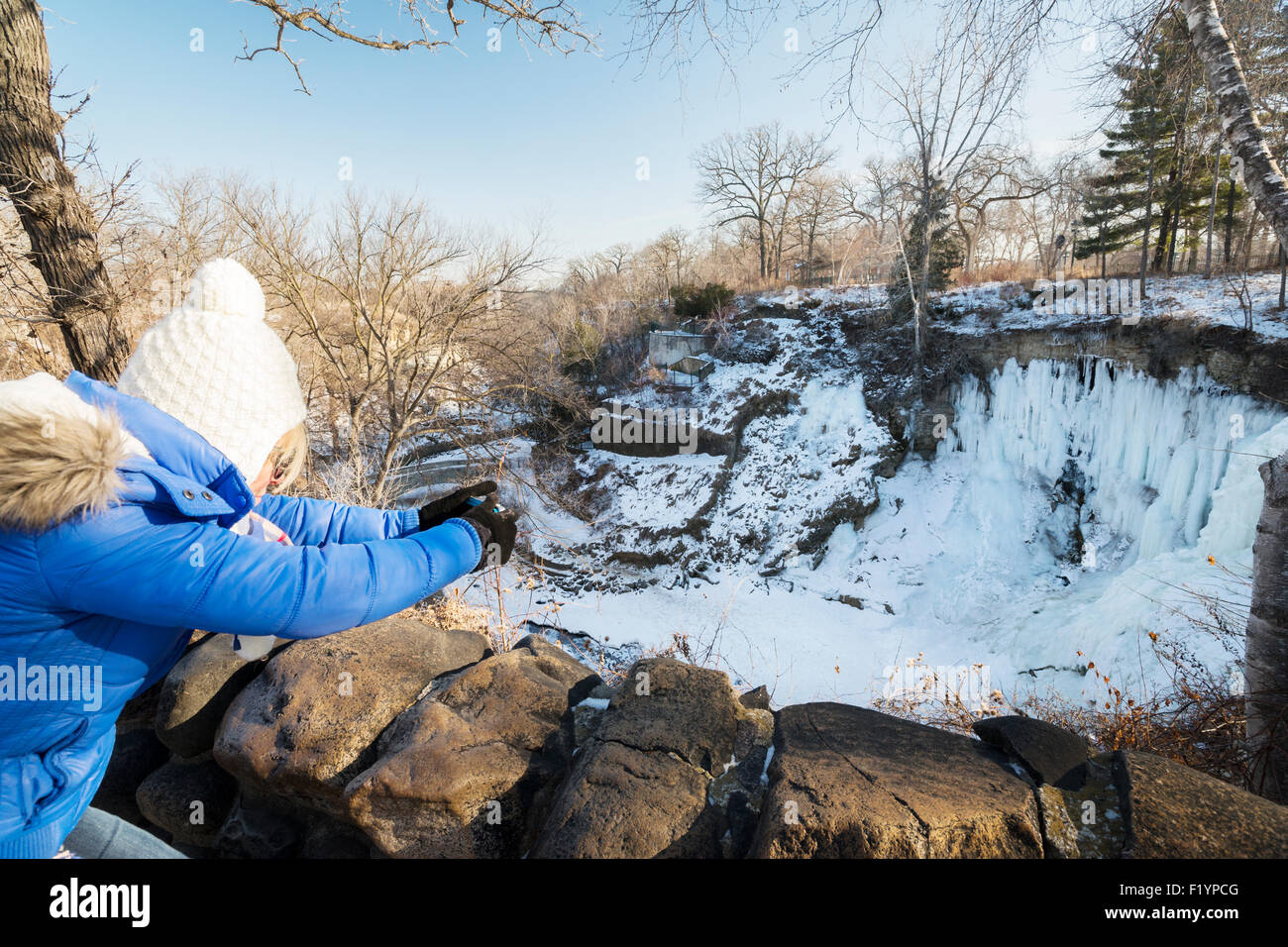 Frau soll Kamera an gefrorenen Minnehaha Falls im Winter, Minneapolis, MN, USA Stockfoto