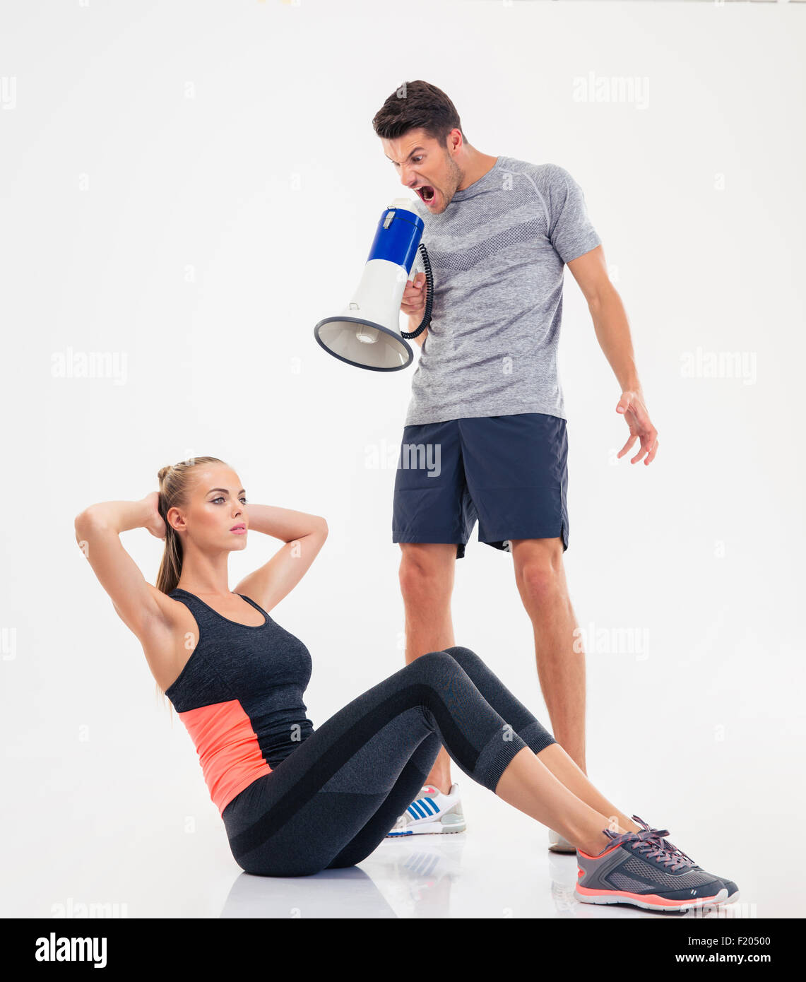 Konzept-Foto eines Trainers schreien über Lautsprecher auf eine Frau, die Übungen auf einem weißen Hintergrund isoliert Stockfoto