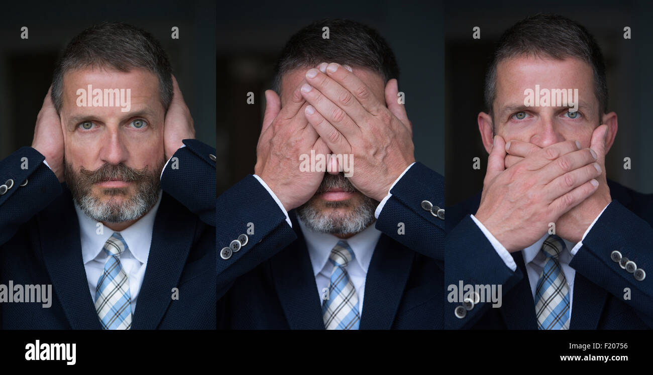 gut aussehender Mann mit Bart und in Anzug und Krawatte posiert als die drei weisen Affen Stockfoto
