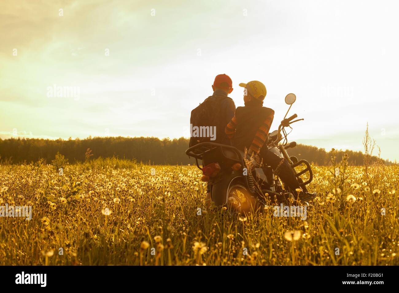 Zwei jungen, sitzen auf dem Motorrad, im Feld, Rückansicht Stockfoto
