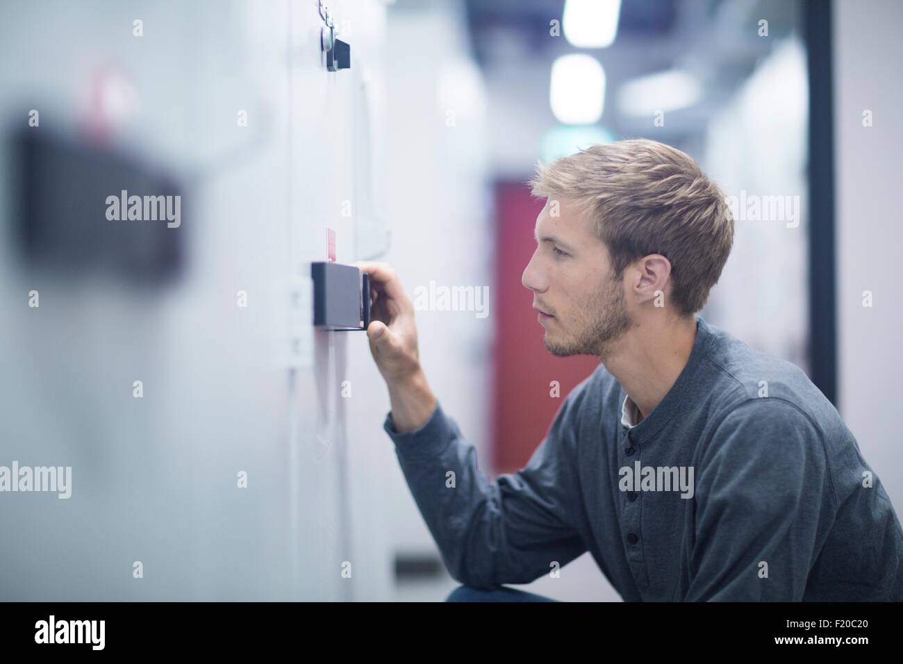 Männliche Techniker hocken um Schalter im Technikraum Stockfoto